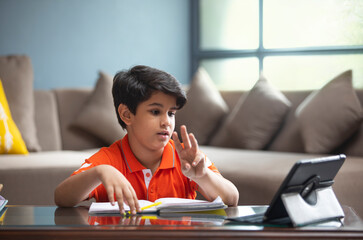 YOUNG BOY ANSWERING TO HIS TEACHER DURING HIS ONLINE CLASS	