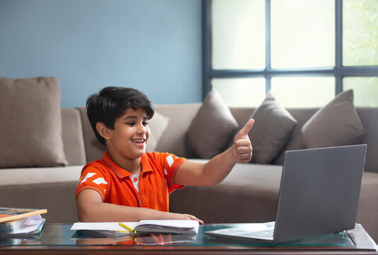 A YOUNG SCHOOL KID SHOWING THUMBS UP DURING ONLINE CLASS	