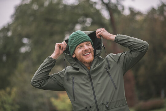 Young Man In A Green Coat Walking In The Rain