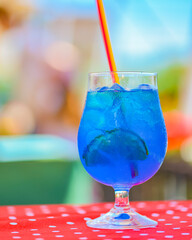 Blue curacao cocktail drink in glass with ice and lemon outside. Cold refreshing summer beverage.