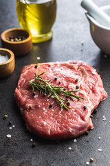 Sliced raw ribeye steak on black kitchen table.