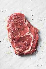 Sliced raw ribeye steak on white kitchen table.