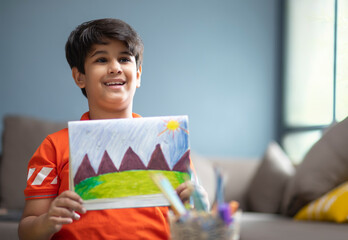 Young boy showing artwork he made at home 