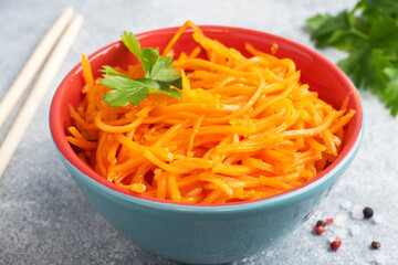 Raw grated spicy carrot salad in bowl. Korean carrot with spices and sauce.