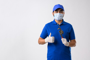 Mechanic in a blue t shirt giving a thumbs up with a spanner wrench in his hand	