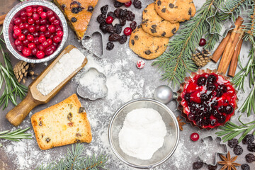 Ingredients for cooking Christmas baking with flour, cookies, fir branches, cranberries