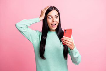 Naklejka premium Photo portrait of shocked woman holding head phone in one hand isolated on pastel pink colored background