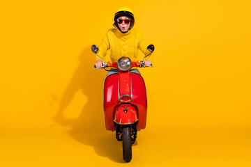 Photo portrait of shocked woman on red retro scooter isolated on vivid yellow colored background © deagreez