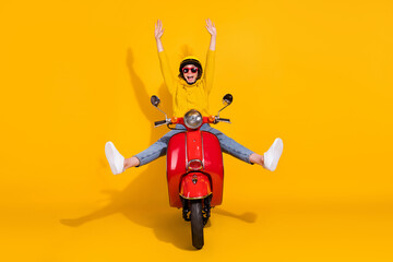 Photo portrait of girl riding red scooter not holding handlebars raising arms spreading legs like star isolated on vivid yellow colored background