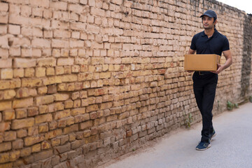 Fototapeta na wymiar Courier boy walking with a parcel in his hand 
