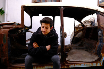 A pensive man sits in an old car. in distress, heartbroken, trouble and preoccupied concept.