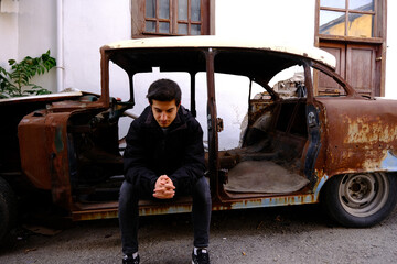 A pensive man sits in an old car. in distress, heartbroken, trouble and preoccupied concept.