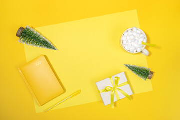 Notepad - organizer on 2021, Xmas trees, cup of coffee with marshmallows, Xmas DIY gift box on yellow with copy space.