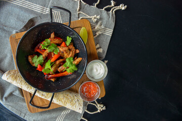 Vegetables and meat in wok pan served with lavash bread and different kinds of sauce. Close up.