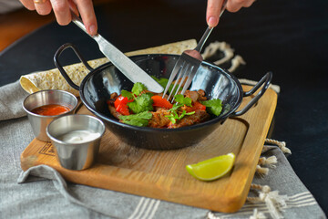 Vegetables and meat in wok pan served with lavash bread and different kinds of sauce. Close up.