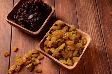 Heaps of yellow and dark Raisins, in a wooden bowls.  Dried Grapes.