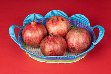 4 red large pomegranate on blue fruit basket