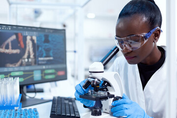 African pharmacology researcher analysing chemical substance using microscope for study.. Black...
