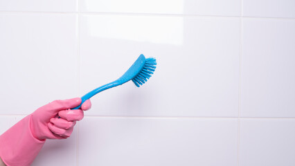 a female hand in a glove holds a washing brush