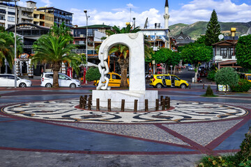 Turkey, Alanya - October 22, 2020: Abstract sculpture with a chain on the promenade in the Alanya Marina. Summer tropical exotic cityscape of tourist town with buildings, mosque and cars on the street