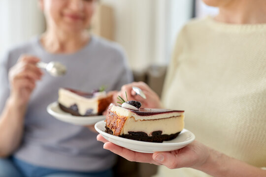 Food, Dessert And People Concept - Close Up Of Women Eating Cake At Home