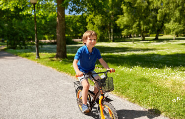 Obraz premium childhood, leisure and people - happy smiling little boy riding bicycle at summer park