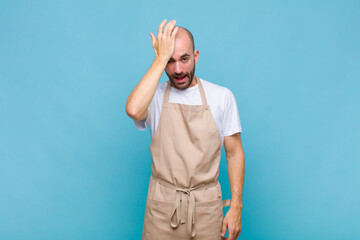 bald man raising palm to forehead thinking oops, after making a stupid mistake or remembering,...