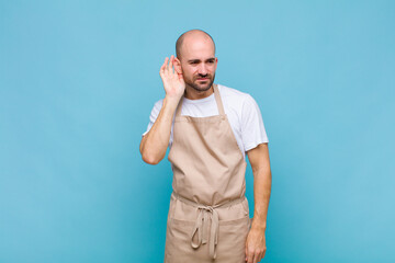 bald man looking serious and curious, listening, trying to hear a secret conversation or gossip,...