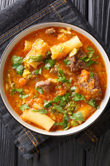 Haitian joumou beef and pumpkin soup closeup in the plate on the table. Vertical top view from above