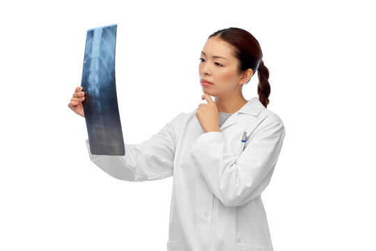 medicine, radiology and healthcare concept - asian female doctor in white coat looking at x-ray scan image of spine