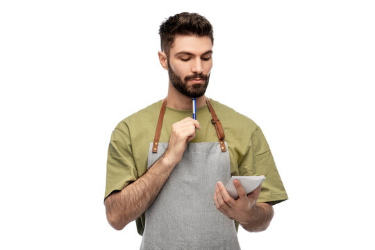 people, profession and job concept - waiter in apron taking notes to notepad over white background