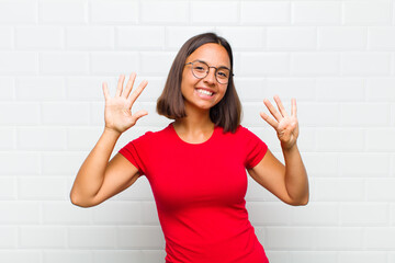 latin woman smiling and looking friendly, showing number nine or ninth with hand forward, counting...