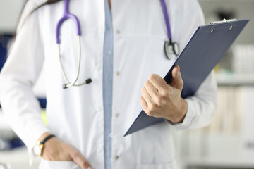 Doctor in white coat holding clipboard with documents in clinic