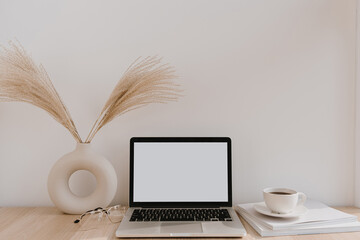 Female home office desk workspace. Blank screen laptop computer with copy space. Coffee cup, pampas grass in stylish vase on beige wooden table. Minimalist lifestyle blog mockup. © Floral Deco