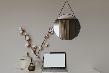 Blank screen laptop. Home office desk table workspace with cotton plant, vase, mirror on grey background. Copy space mockup blog, website template. Blogger, outsourcing freelancer hero header.