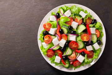 Plate of fresh salad with vegetables, feta cheese and olives. Greek salad. Top view
