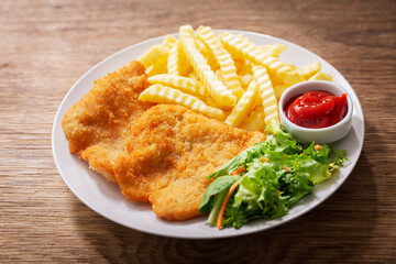 plate of fried breaded chicken meat or Schnitzel with french fries and salad