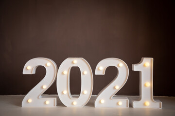 Figures 2021 with lights on brown background. Merry Christmas and Happy New Year 2021
