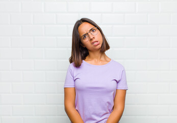 latin woman feeling puzzled and confused, with a dumb, stunned expression looking at something...