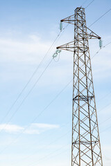 poles of powerpoles of power lines in a field against a blue sky, bottom-up view, vertical position lines in the field