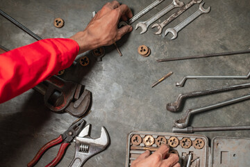 image of mechanical hands with several workshop tools on the floor, wrenches, wrenches, pipe wrenches, pliers and bolts
