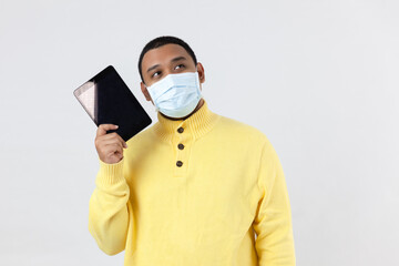 Fototapeta na wymiar Asian man in a yellow shirt wearing protact mask look up holding tablet on white background