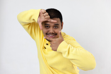 Asia man standing over isolated white background smiling making frame with hands and fingers with happy face
