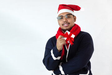 Asian man wearing a santa hat is standing on a white back ground posing point to camera