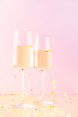 Two glasses of champagne or wine on the pink background, creative festive composition