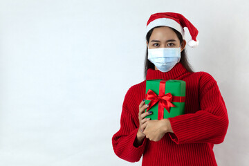 young asian woman wear a protective mask covid-19 holding gift box looking camera on white background
