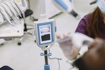 Obraz premium Young african-american man. Guy visiting dentist's office for prevention of the oral cavity. Man and famale doctor while checkup teeth.