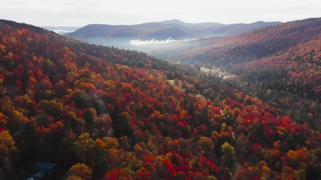 Vermont mountains hillsides with colorful vibrant cover of Autumn leaf color, dolly in aerial