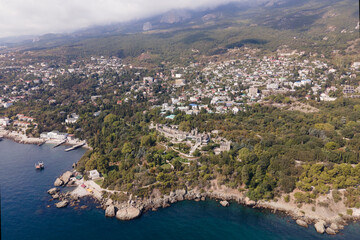 Fototapeta premium Aerial drone photo of Vorontsov palace, huge green famous garden against the mountains hidden in fog in sunny day, sightseeing in the Crimea