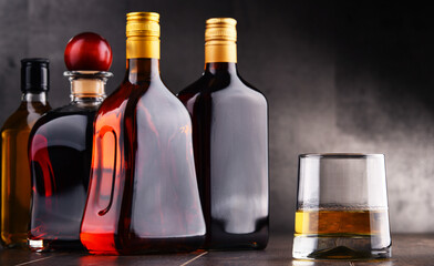 Glass and bottles of assorted alcoholic beverages.